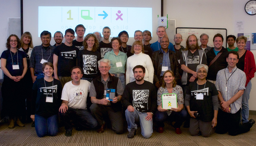 OLPC community group holding the printed summit materials.